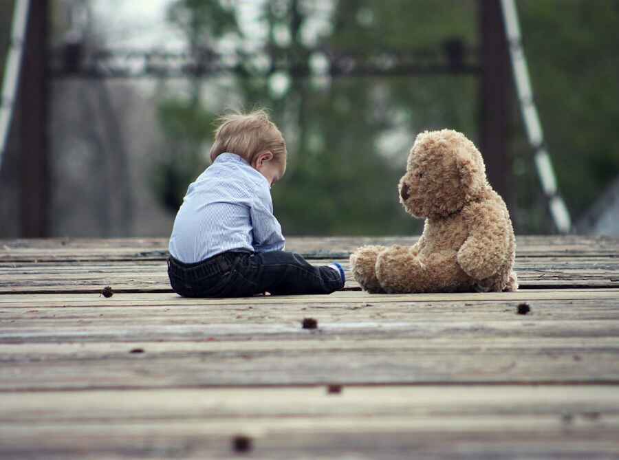 Childhood concept shown as a small boy with a teddy.