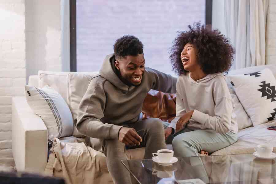 Couple laughing whilst sitting on a couch