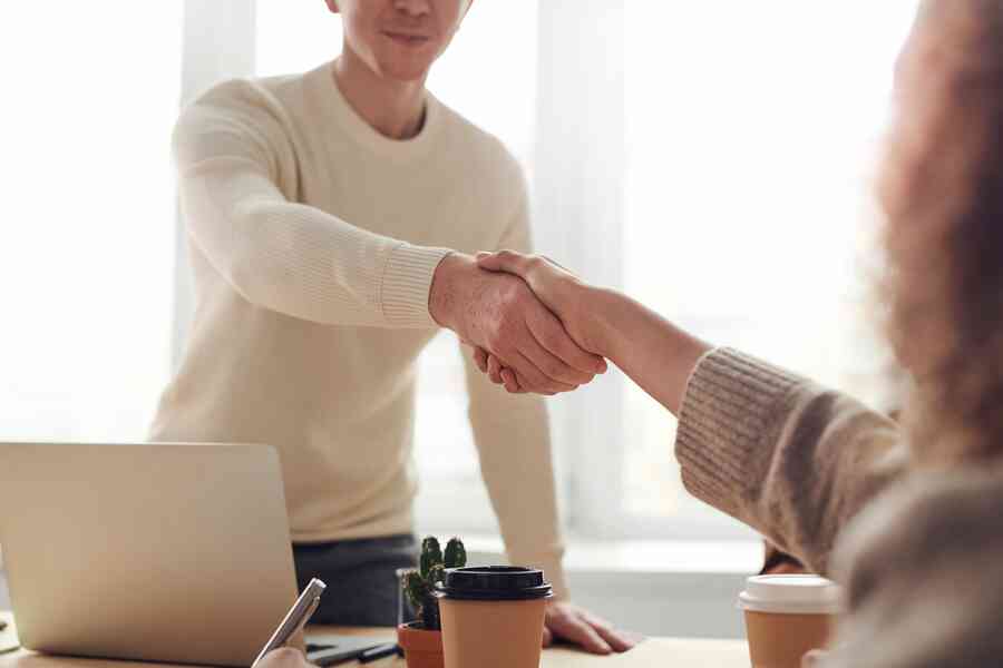 Man and woman shaking hands over a table